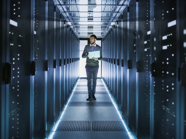 IT-Techniker arbeitet an einem Laptop in einem großen Datenzentrum 